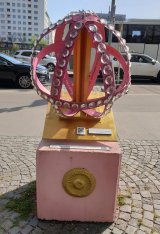 2025 Neugestaltung des rosa Globus. Bestückt mit Glaskristallen und auf der Innenseite von Passanten in vielen Sprachen mit "Glück haben, Glück brauchen, Glück wünschen" beschrieben.   